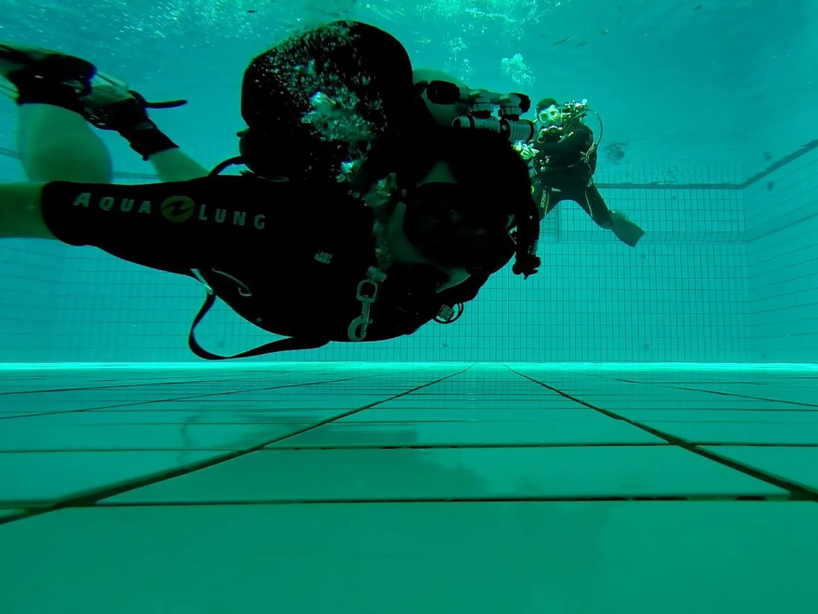 Zwei Taucher mit vollständiger Ausrüstung waagrecht im Schwimmbecken