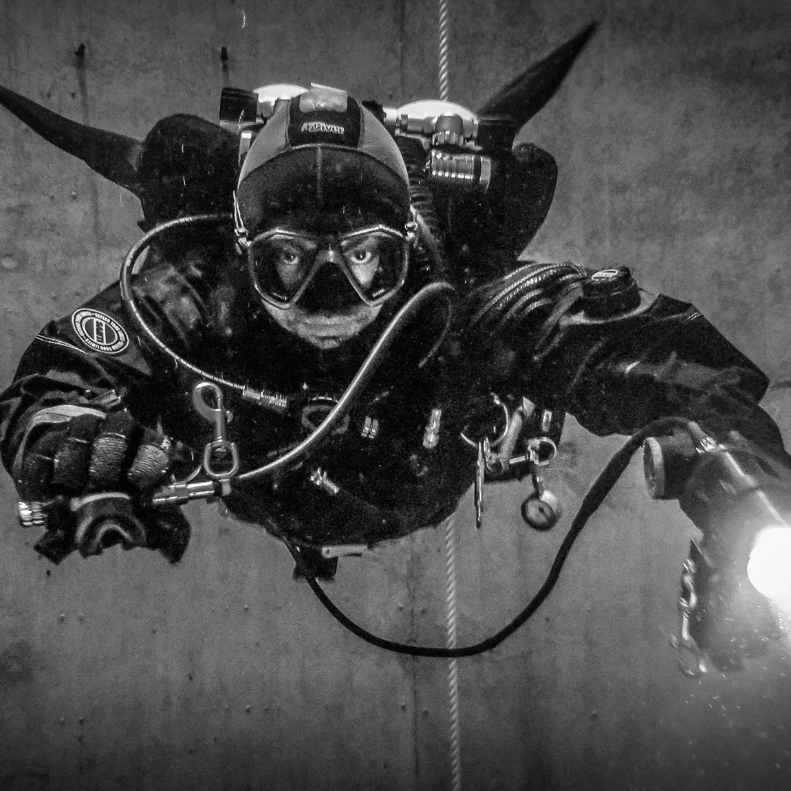 Technischer Taucher mit Rebreather an einer Wand, Schwarzweiss